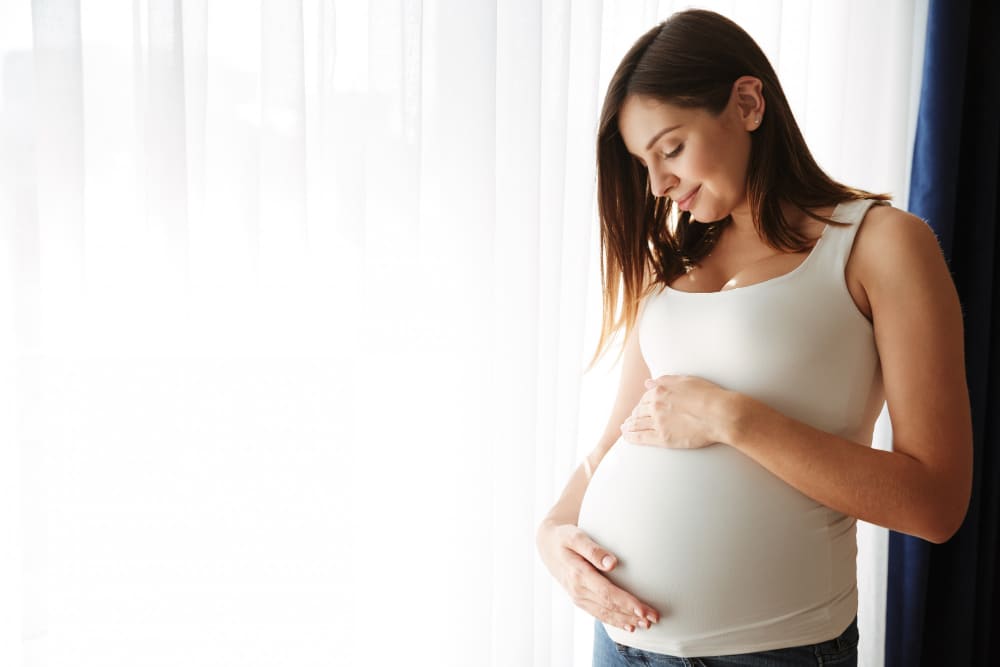 Mujer embarazada cerca de la cortina