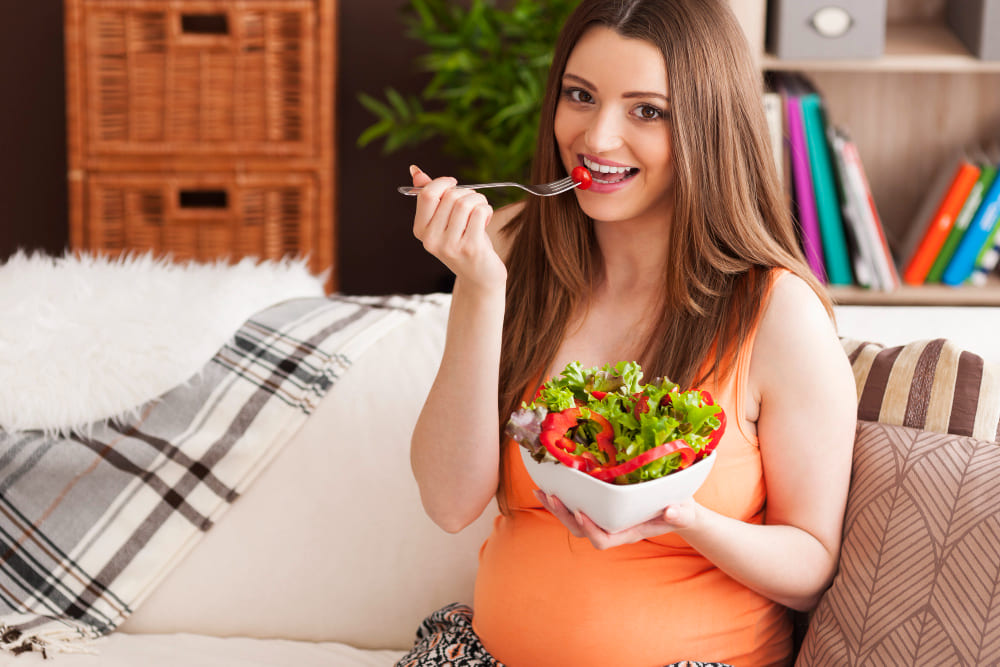 Mujer embarazada comiendo ensalada